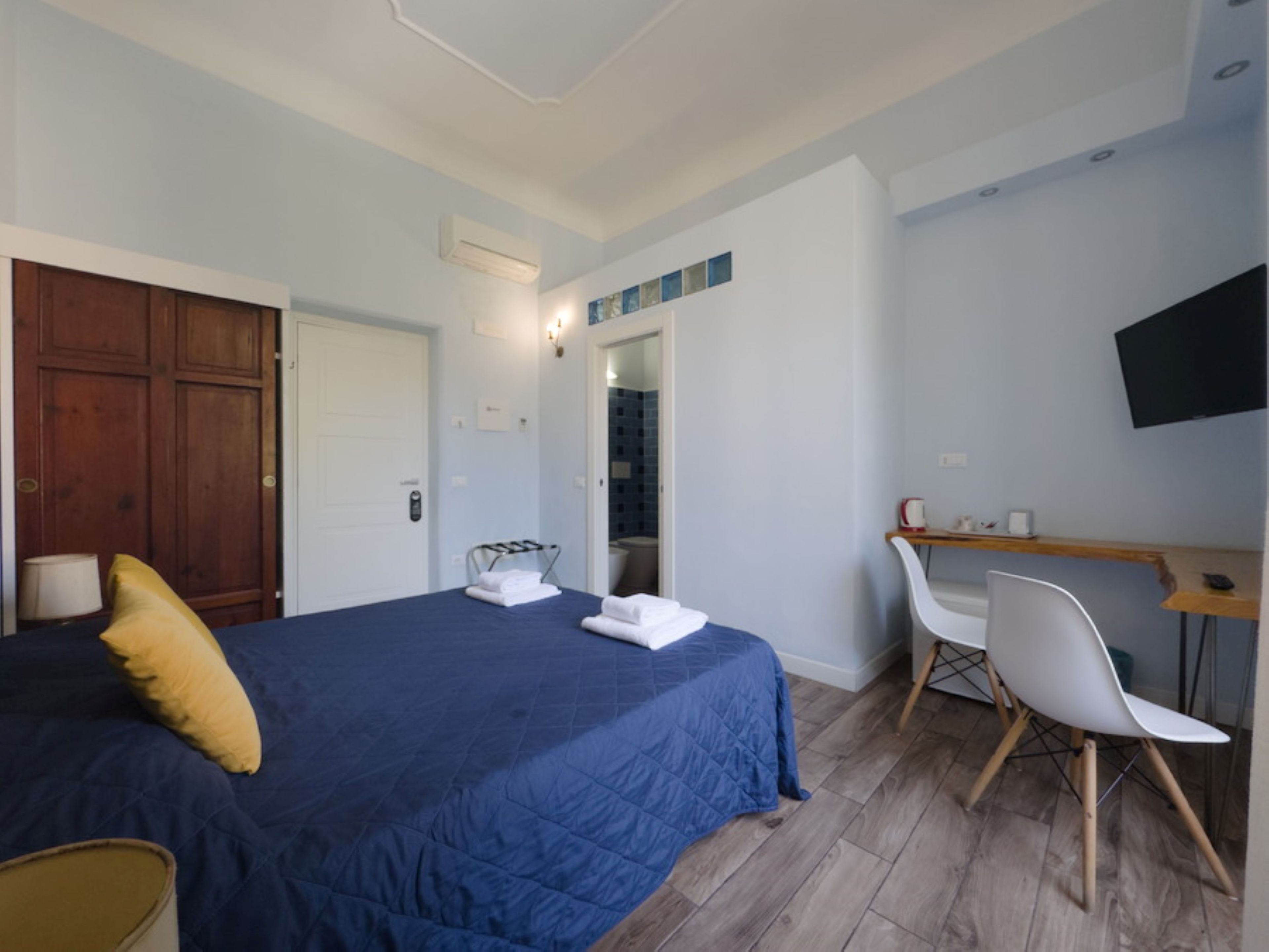 Una camera da letto con un letto, una scrivania, una sedia, una televisione e un armadio.