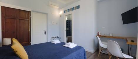 Ein Schlafzimmer mit Bett, Schreibtisch, Stuhl, Fernseher und Kleiderschrank.