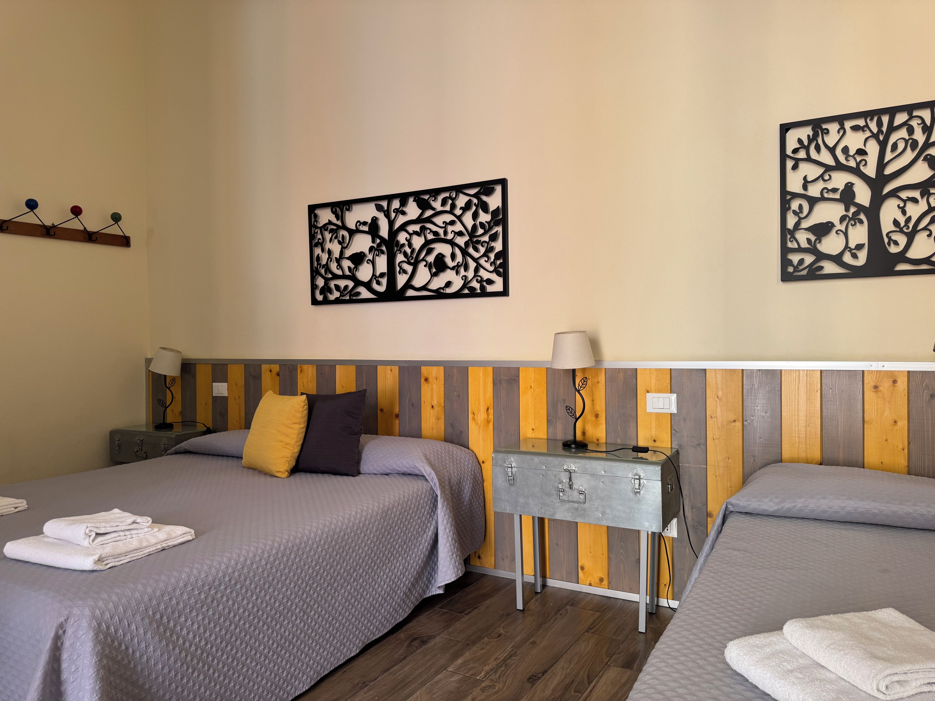 Ein Hotelzimmer mit zwei Betten, einem Holzkopfteil, einem Nachttisch mit Lampe sowie Wanddekoration.
