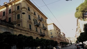 Vista de una calle con una hilera de edificios de estilo europeo clásico, con balcones y ventanas arqueadas.
