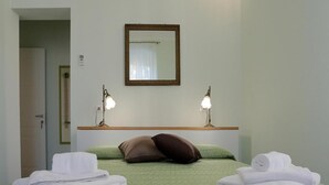 Une chambre d’hôtel avec une couvre-lit verte, deux oreillers, un miroir et deux lampes de chevet.