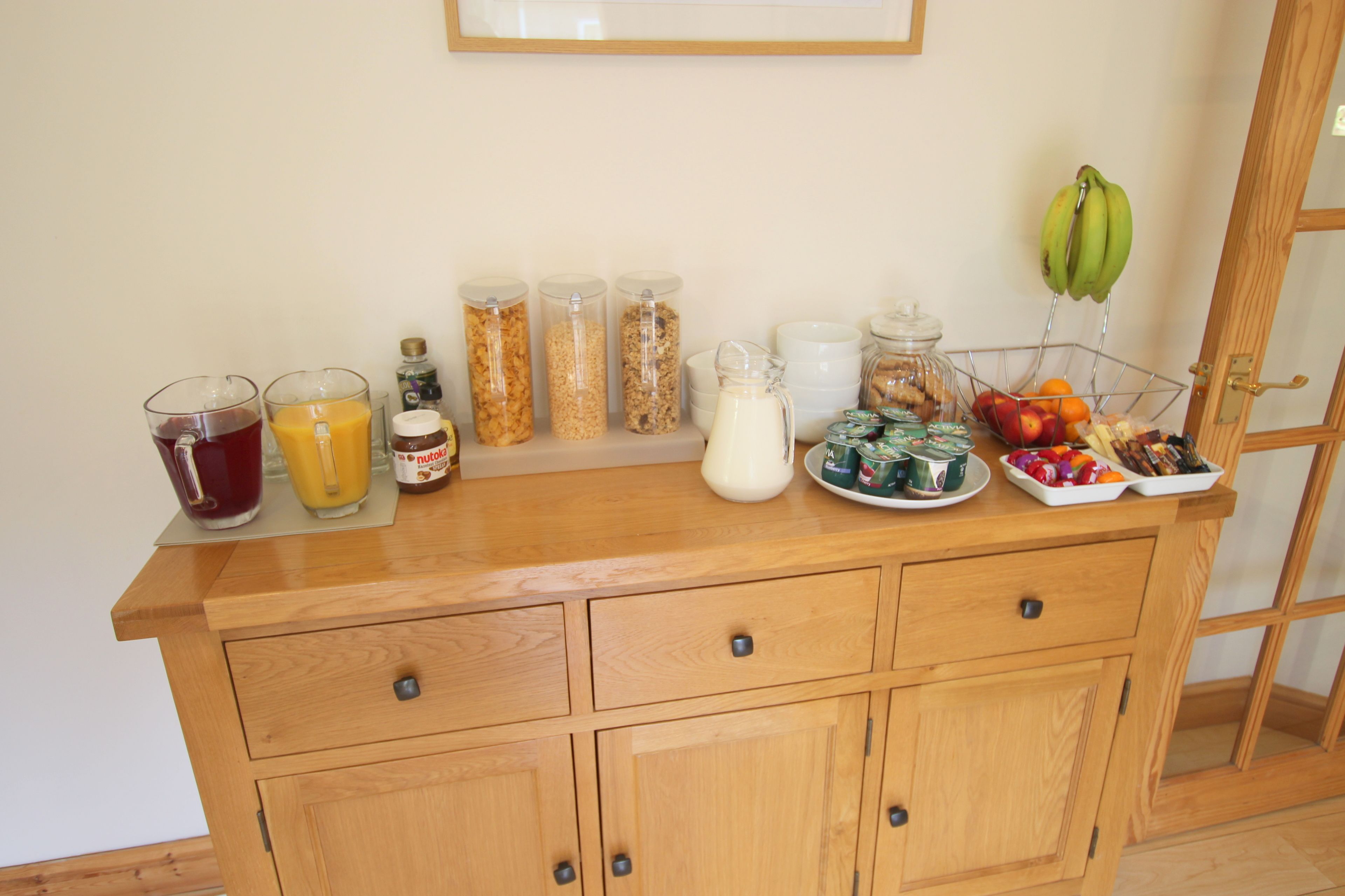 A wooden buffet table with various food items and beverages.