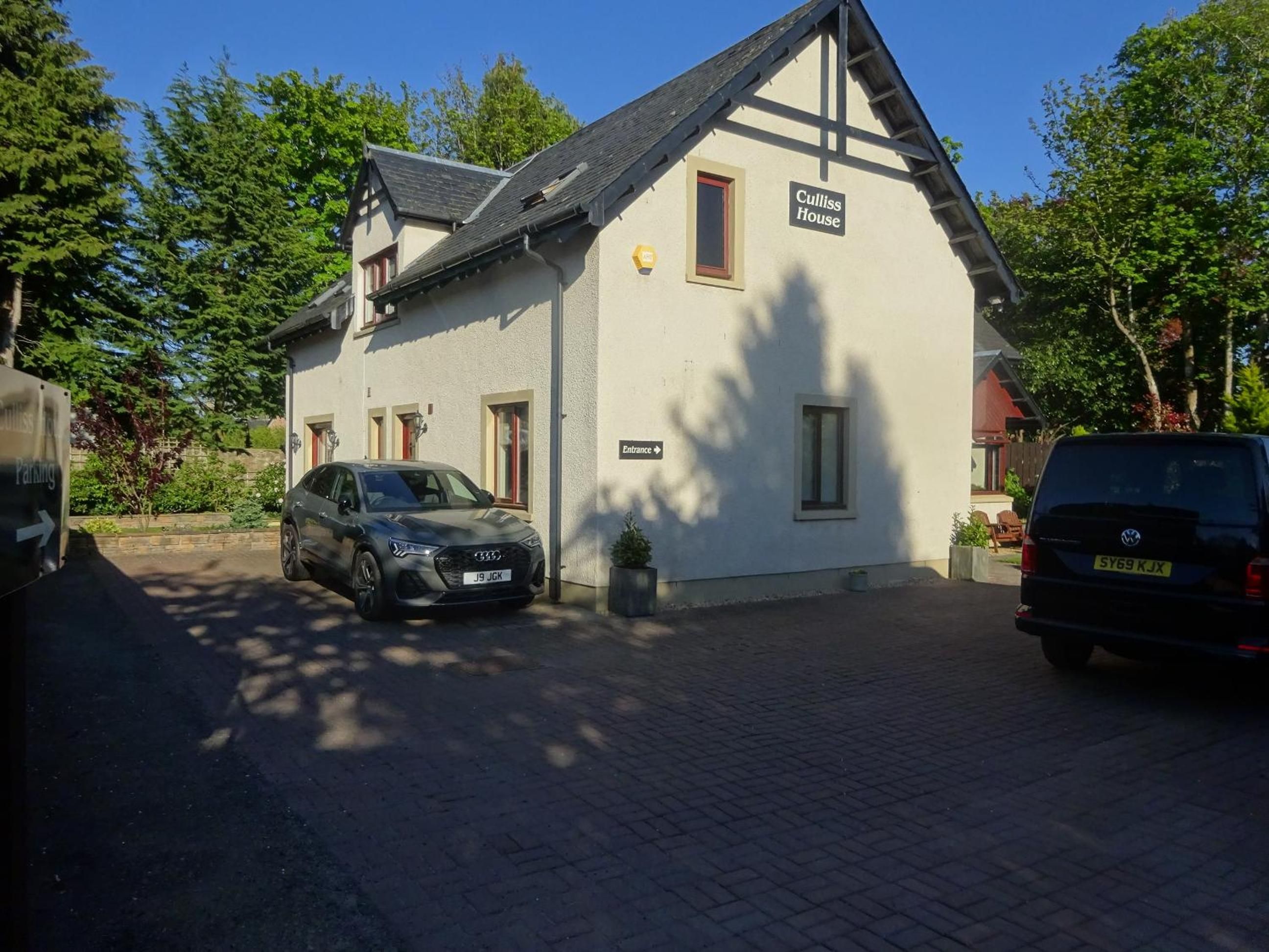 A two-story house with a sign reading 'Culliss House' and a car parked in front.