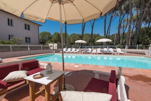 Una piscina al aire libre, sombrillas, sillones reclinables de piscina