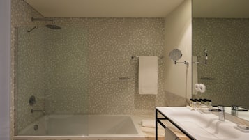 A modern bathroom with a glass-enclosed shower, a large bathtub, and a vanity with a mirror.
