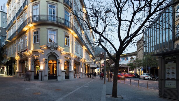 A historic building with ornate architecture, a cobblestone street, and a pedestrian area.