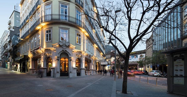 Un edificio histórico con arquitectura ornamentada, una calle adoquinada y una zona peatonal.