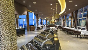 A modern hotel lobby with a long buffet line, a mosaic pillar, and a view of the cityscape through large windows. - Protea Hotel by Marriott Kampala Skyz (Kampala)