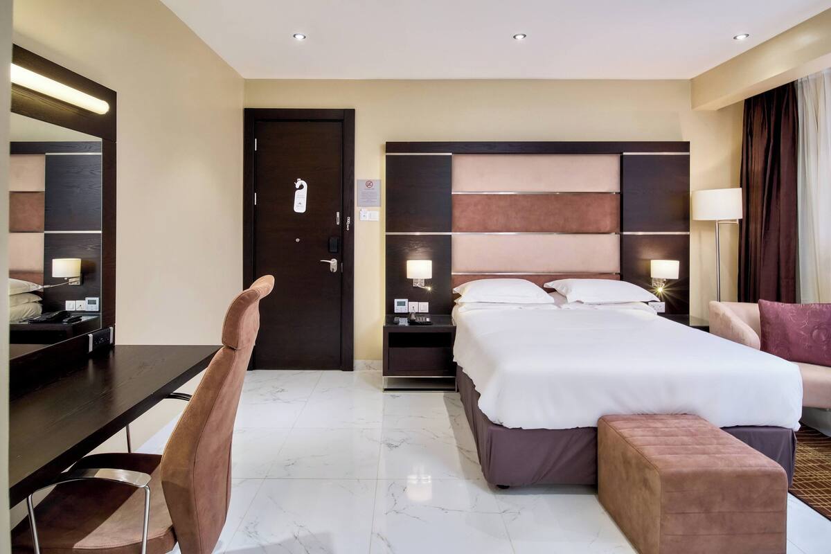 Une chambre d’hôtel avec un grand lit, un bureau, une chaise et une table de chevet.