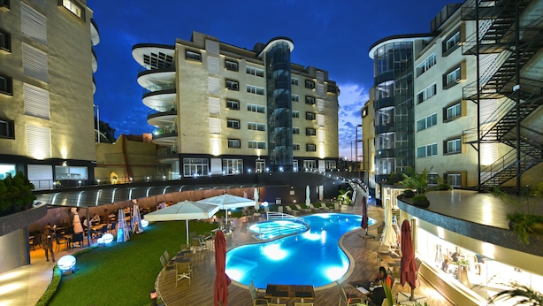 A hotel with a swimming pool, outdoor seating, and multiple floors with balconies. - Protea Hotel by Marriott Kampala Skyz (Kampala)