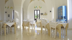 Un espace repas avec des tables dressées pour les repas, des chaises et des lampes suspendues.