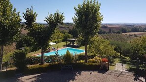 A pool area with a view of the countryside, surrounded by trees and a gazebo. - Agriturismo il Poggiarello (Siena)