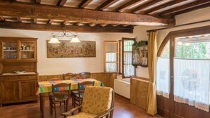 A dining area with wooden furniture, a table with a colorful tablecloth, and a large painting on the wall. - Agriturismo il Poggiarello (Siena)
