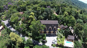 An aerial view of a house surrounded by dense greenery, with a visible swimming pool and a satellite dish. - Pousada Solar das Montanhas (Itatiaia)