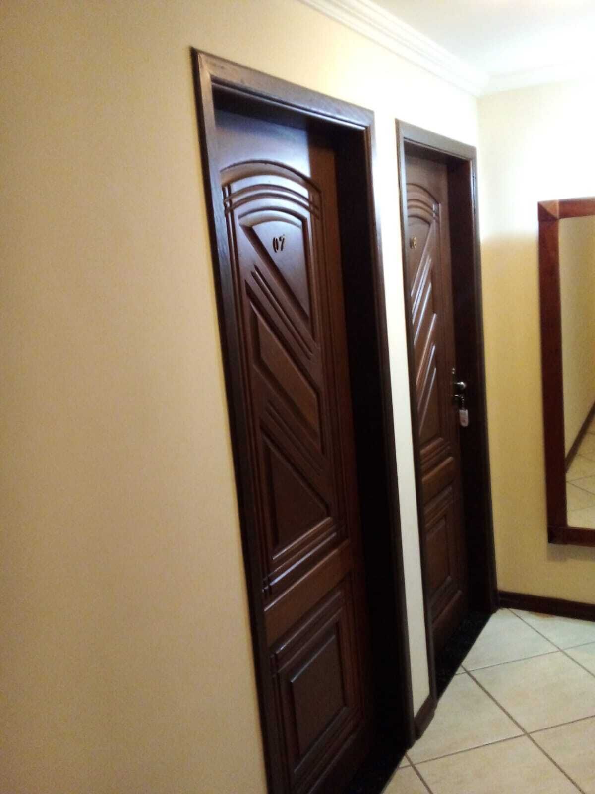 A hallway with two dark wooden doors, one with a number '07' on it, and a tiled floor.