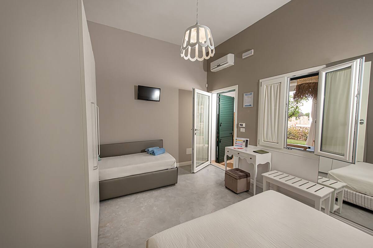 Ein Schlafzimmer mit Bett, Schreibtisch, Stuhl, Fernseher und Fenster.