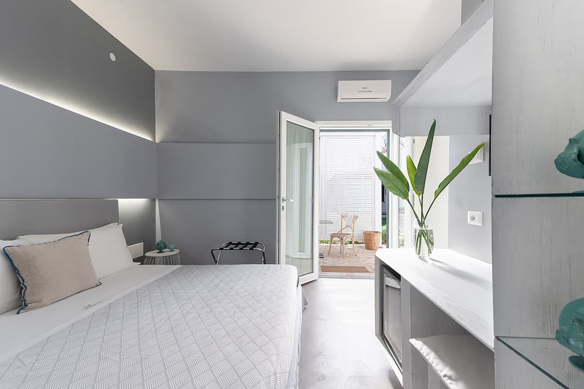 Ein modernes Schlafzimmer mit Bett, Nachttisch und Blick ins Freie.