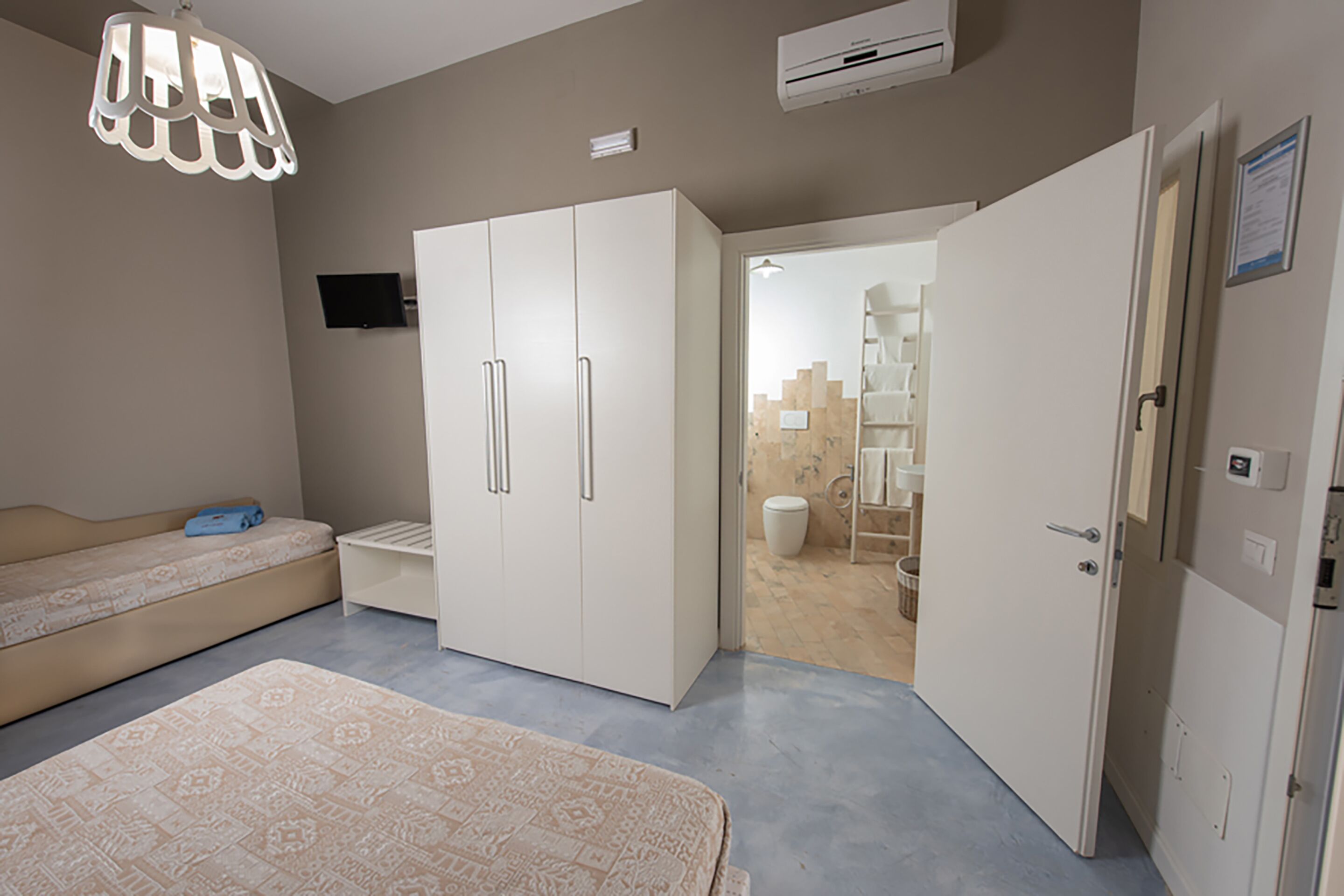 Habitación con cama, armario y baño visible a través de una puerta abierta.