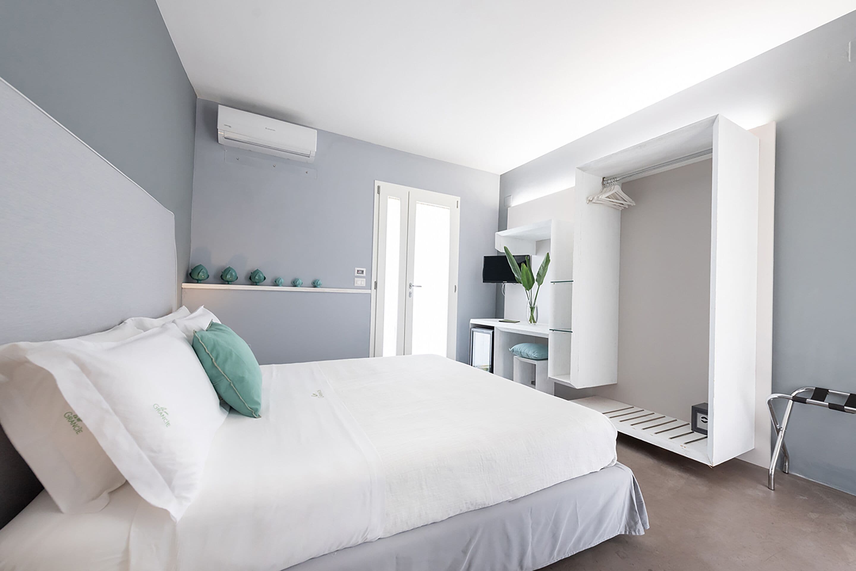 Une chambre d’hôtel moderne avec un grand lit, un bureau avec une chaise, un miroir et une armoire.