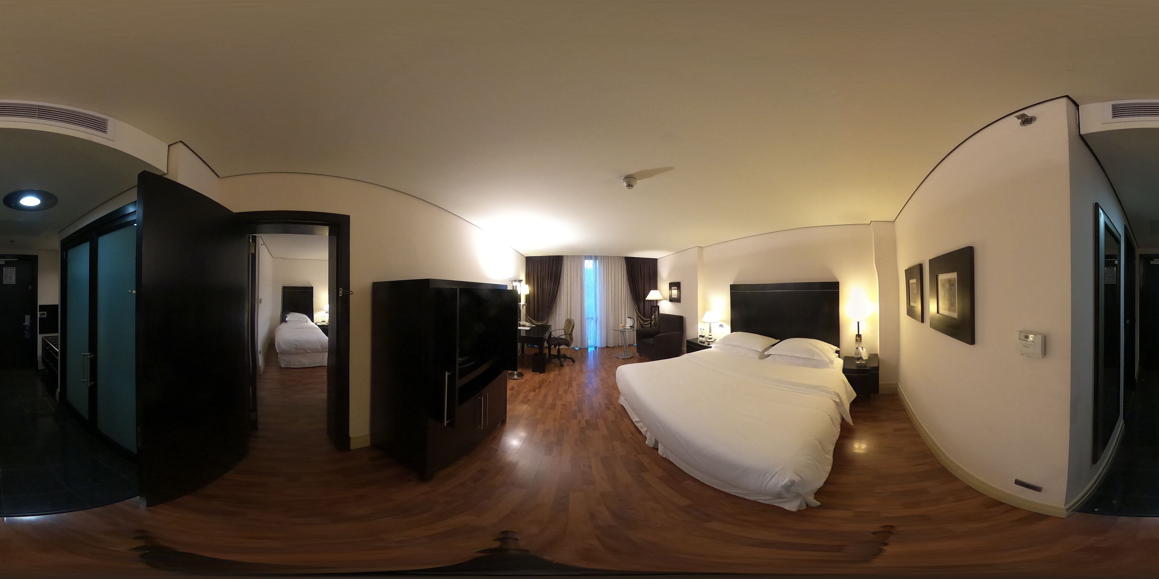 Ein Hotelzimmer mit einem großen Bett, einem Fernseher, einem Schreibtisch und einem Sessel.