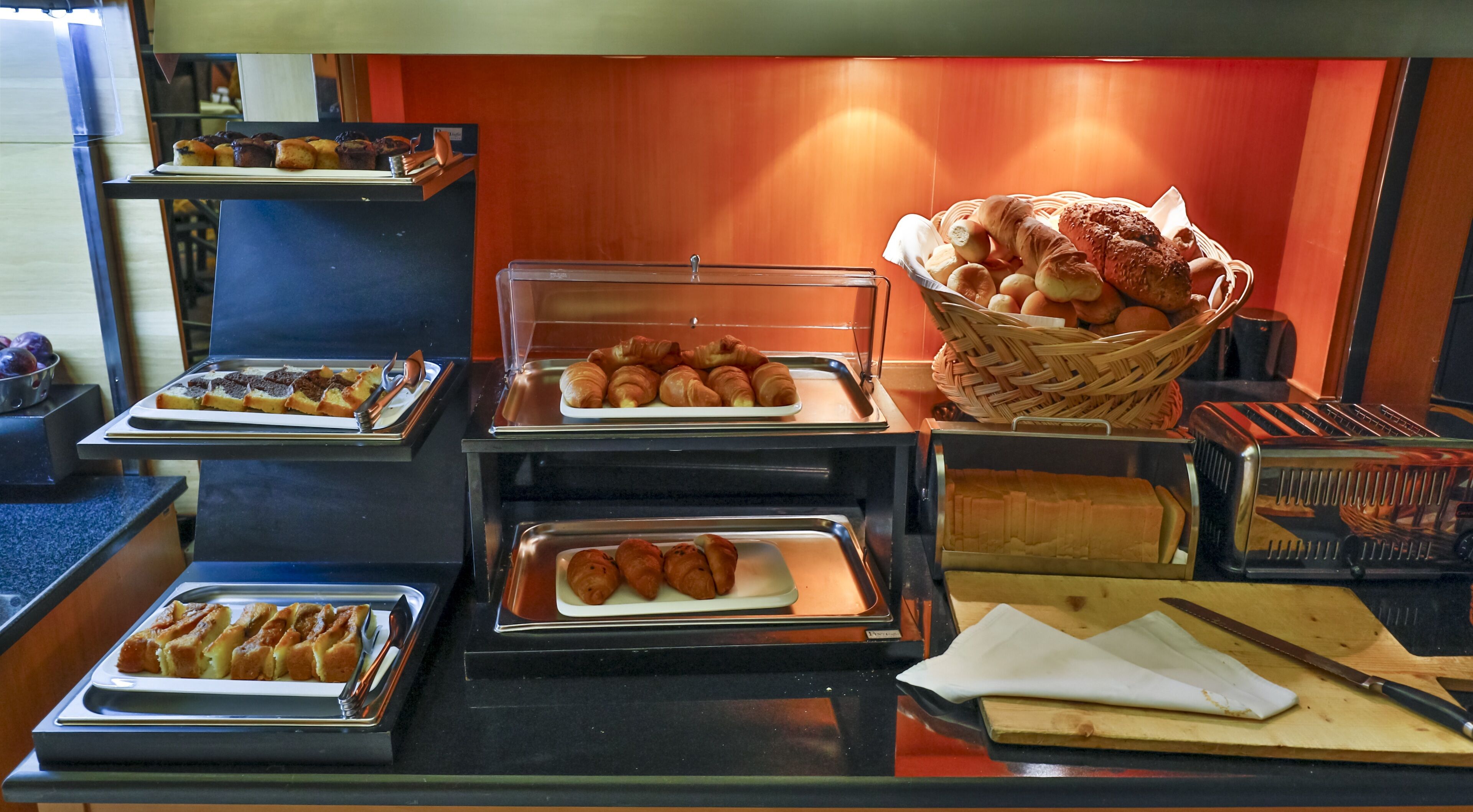 A buffet with various baked goods and pastries displayed in trays.