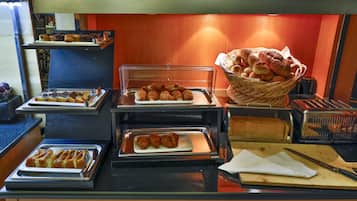 A buffet with various baked goods and pastries displayed in trays.