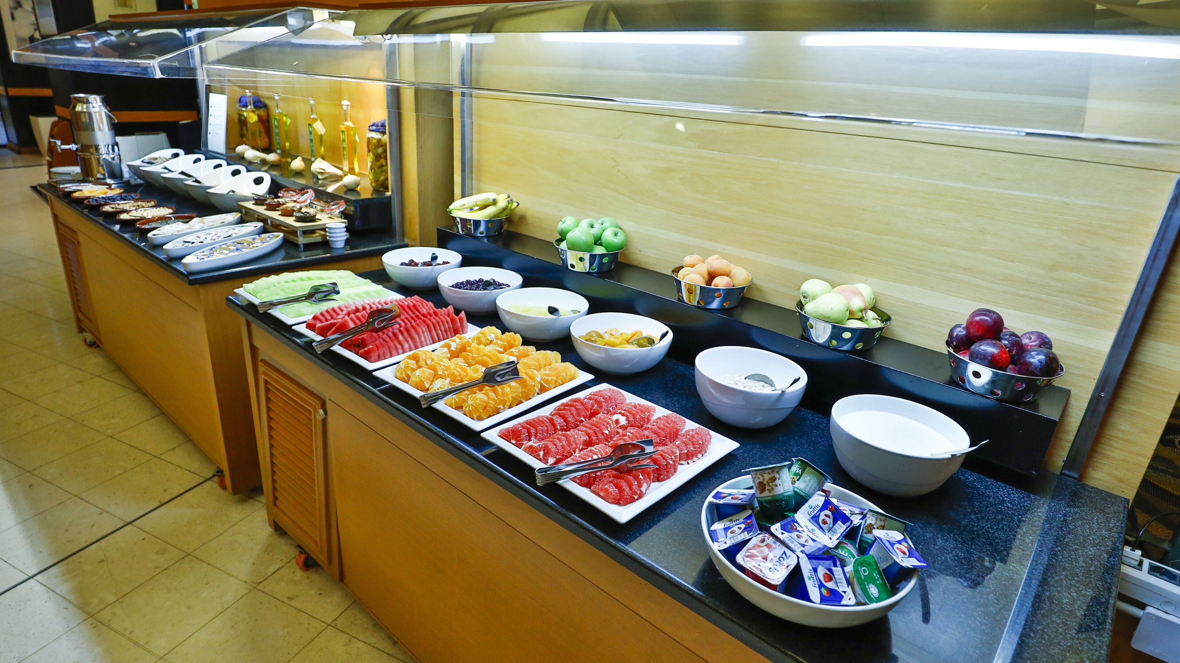 A buffet with various fruits, vegetables, and condiments.