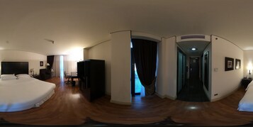 Habitación de hotel con una cama grande, un escritorio, una silla, un televisor y un armario.