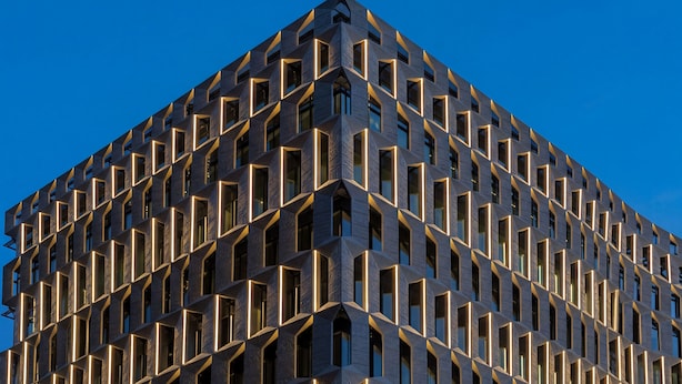 Um edifício moderno com fachada geométrica e padrão uniforme nas janelas.