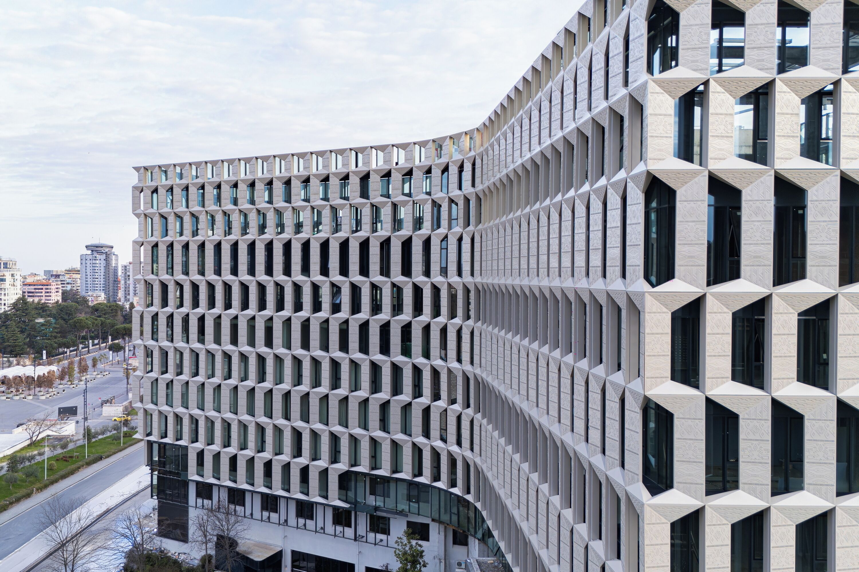 Een modern gebouw met een unieke geometrische gevel, grote ramen en een golvend ontwerp.
