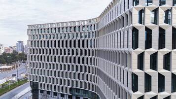 Un edificio moderno con una fachada geométrica única, ventanas amplias y un diseño curvo.
