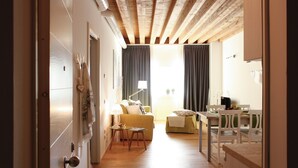 Una sala de estar moderna con techo de madera, un sofá, una mesa de comedor con sillas y una zona de cocina.