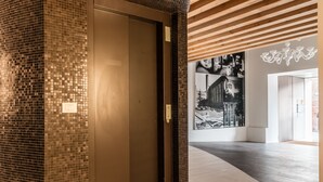 Un interior moderno con un muro revestido de mosaicos, un techo de madera y un gran mural en blanco y negro.