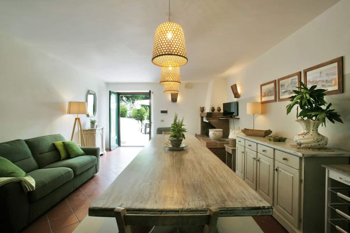 Une cuisine moderne avec une table en bois, un canapé vert et des luminaires suspendus.