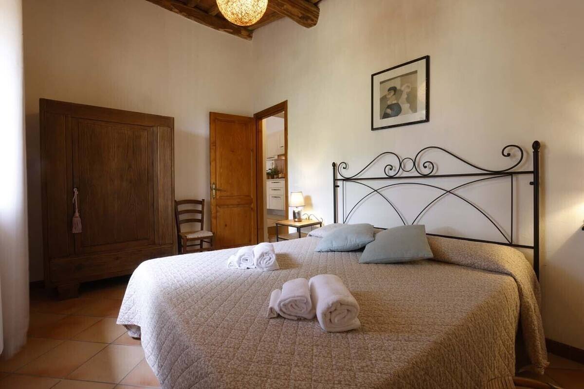 Une chambre à coucher avec un grand lit, une armoire en bois, une chaise et un tableau encadré au mur.