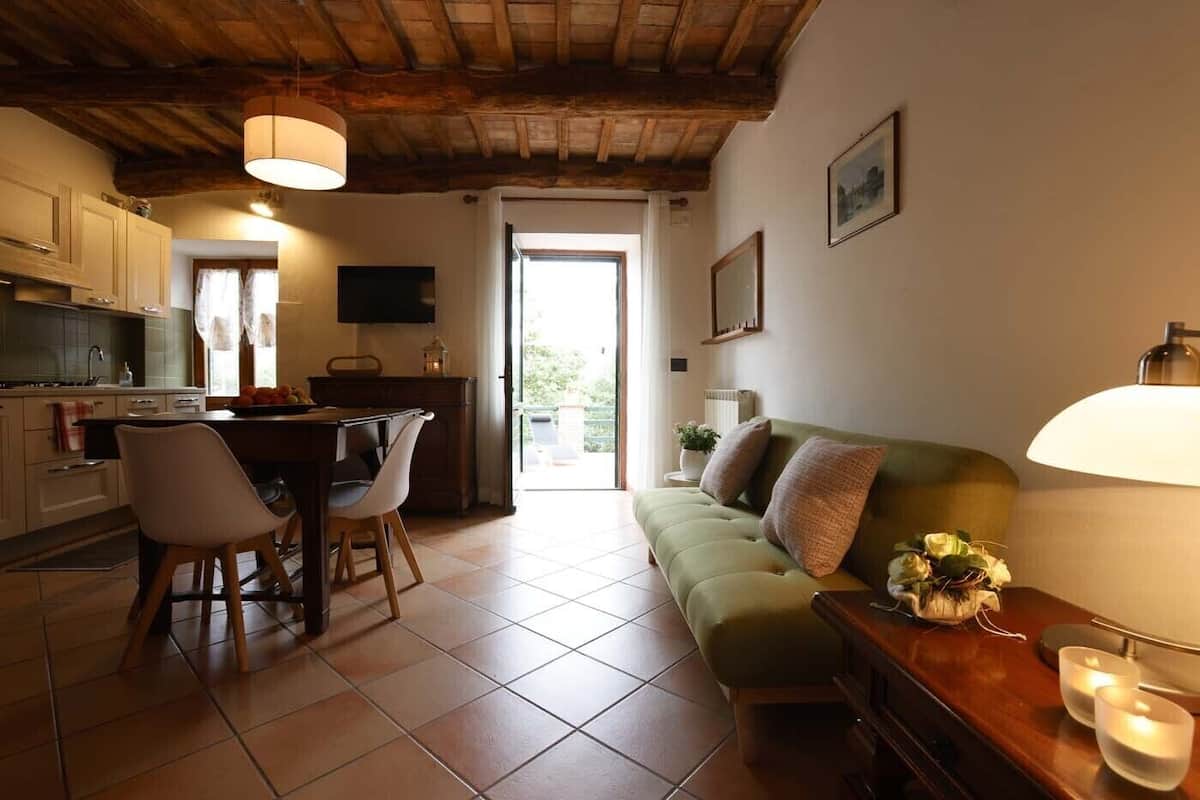 Un espace de vie chaleureux comprenant un canapé, une table à manger avec des chaises, un coin cuisine et un téléviseur.
