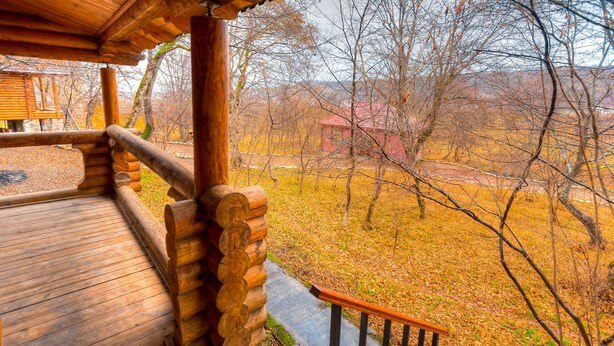 A wooden deck with a stone pathway leading to a red building in a wooded area. - Chateau Qusar (Qusar)