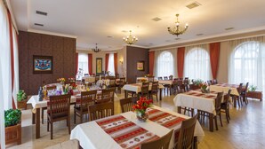 A spacious dining area with multiple tables and chairs, large windows with curtains, and decorative wall art. - Chateau Qusar (Qusar)