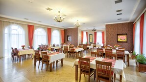 A spacious dining area with multiple tables and chairs, large windows with curtains, and decorative wall art. - Chateau Qusar (Qusar)