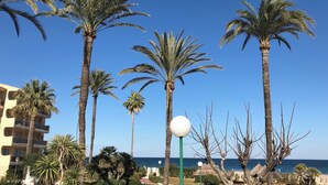 A beachfront hotel with palm trees, a pool, and a view of the sea. - 1ªLínie! Directly on the beach, sea view, pool, air conditioning, WIFI, close to town (Denia)