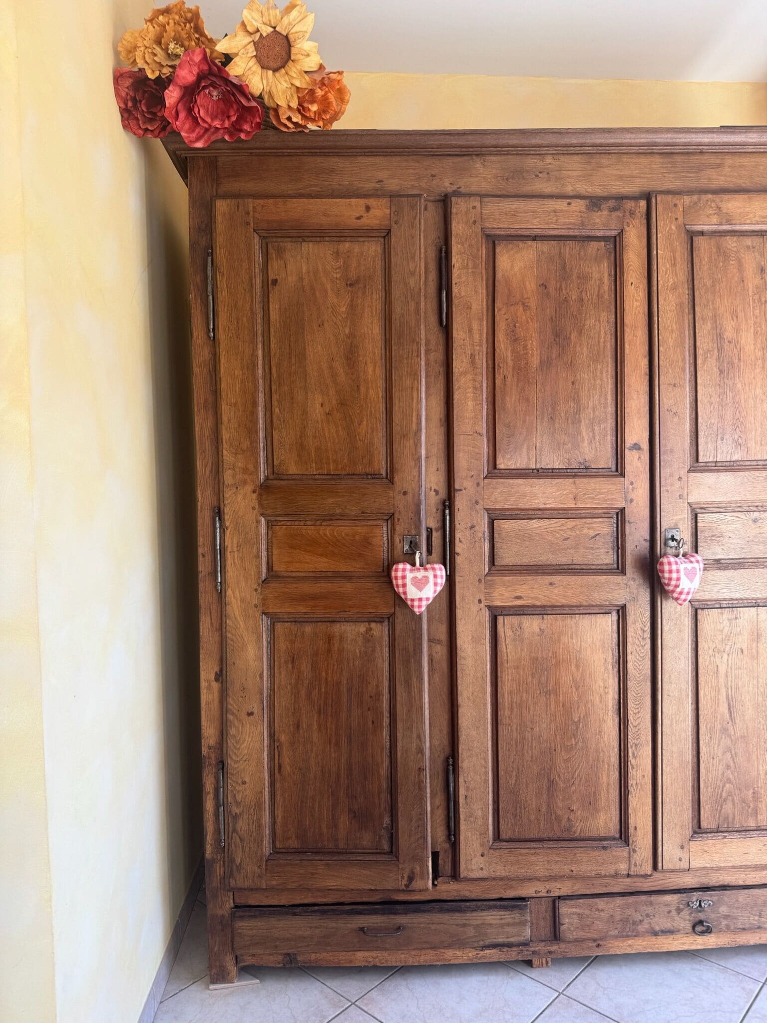 Un armario de madera con dos puertas, un cajón pequeño y un atril con forma de corazón para las llaves.