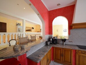 A kitchen with a marble countertop, wooden cabinets, and a red accent wall.