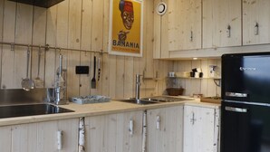 Una cocina con armarios de madera, un refrigerador negro y un cartel en la pared.