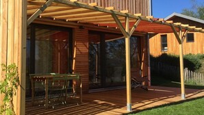 Una terraza de madera con pérgola, una mesa y sillas.