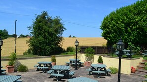 An outdoor seating area with picnic tables and potted plants. - The Tap House (Ashby-de-la-Zouch)