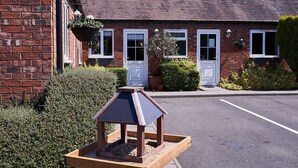 A brick building with a tiled roof, white-framed windows, and a wooden bird feeder in the foreground. - The Tap House (Ashby-de-la-Zouch)