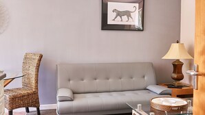 A living room with a grey sofa, wicker chair, glass coffee table, and a framed picture of a leopard on the wall. - The Tap House (Ashby-de-la-Zouch)