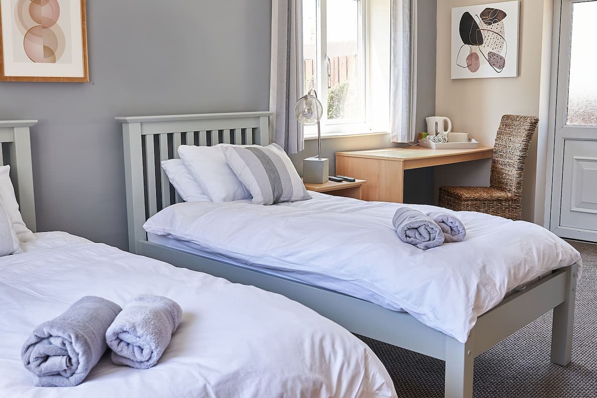 Ein Hotelzimmer mit zwei Betten, einem Schreibtisch, einem Stuhl und Bildern an den Wänden.