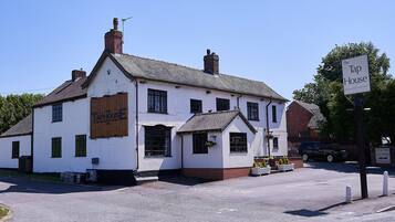 A white building with a sign reading "The Tap House" and a smaller sign indicating a car park.