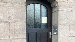 A dark-colored door with a glass panel, a small mailbox, and a doorbell. - Harsdörffer Apartment (Nuremberg)